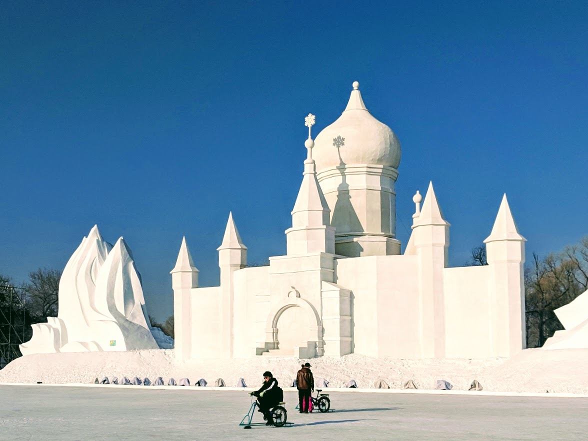 Ice biking in front of massive snow sculptures in Harbin China