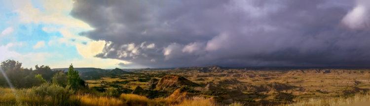 painted canyon (trnp) with sunshine on one side and storm clouds on the other