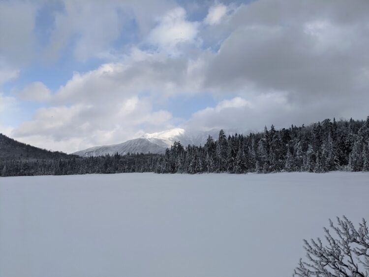 frozen lonesome lake with mountain summit in background