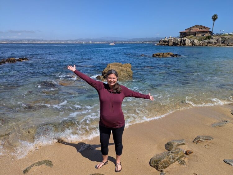 pregnant woman showing off baby bump on a California beach