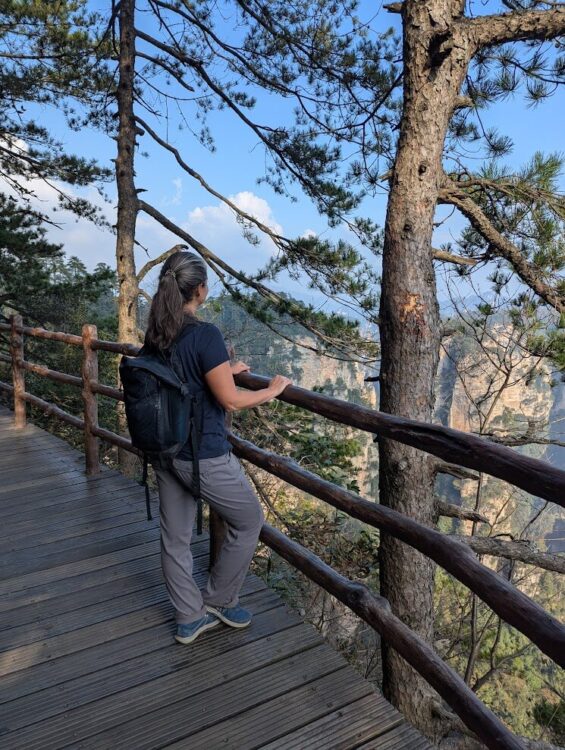 Woman with backpack looking out over mountain gorge in Zhangjiajie, China